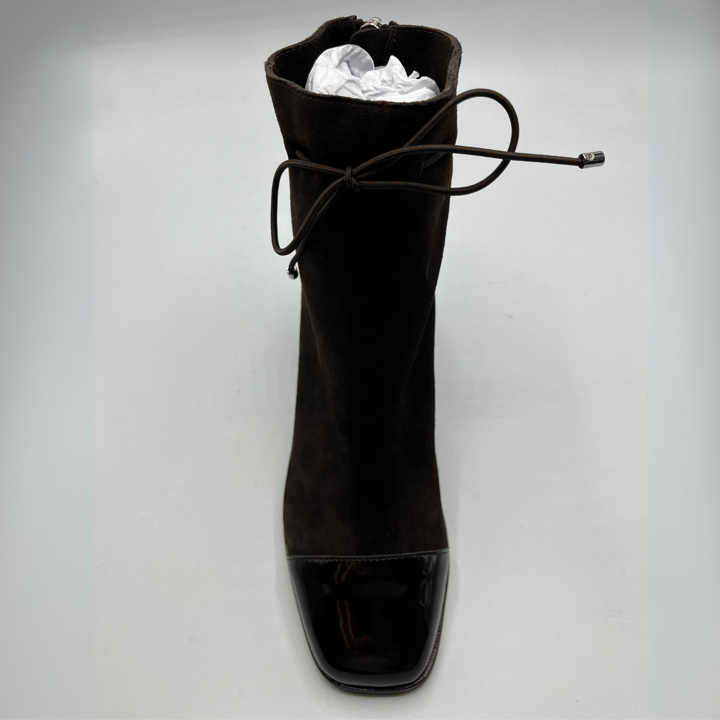 Front view of a chocolate leather with a chocolate patent leather toe cap. Stacked heel and unique tie up ankle