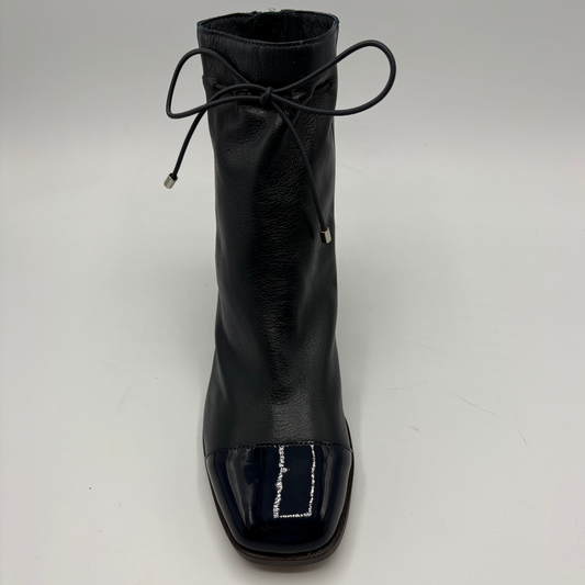 A single navy leather ankle boot with a glossy patent leather toe cap and a thin black lace tied at the collar, shown against a plain light gray background.