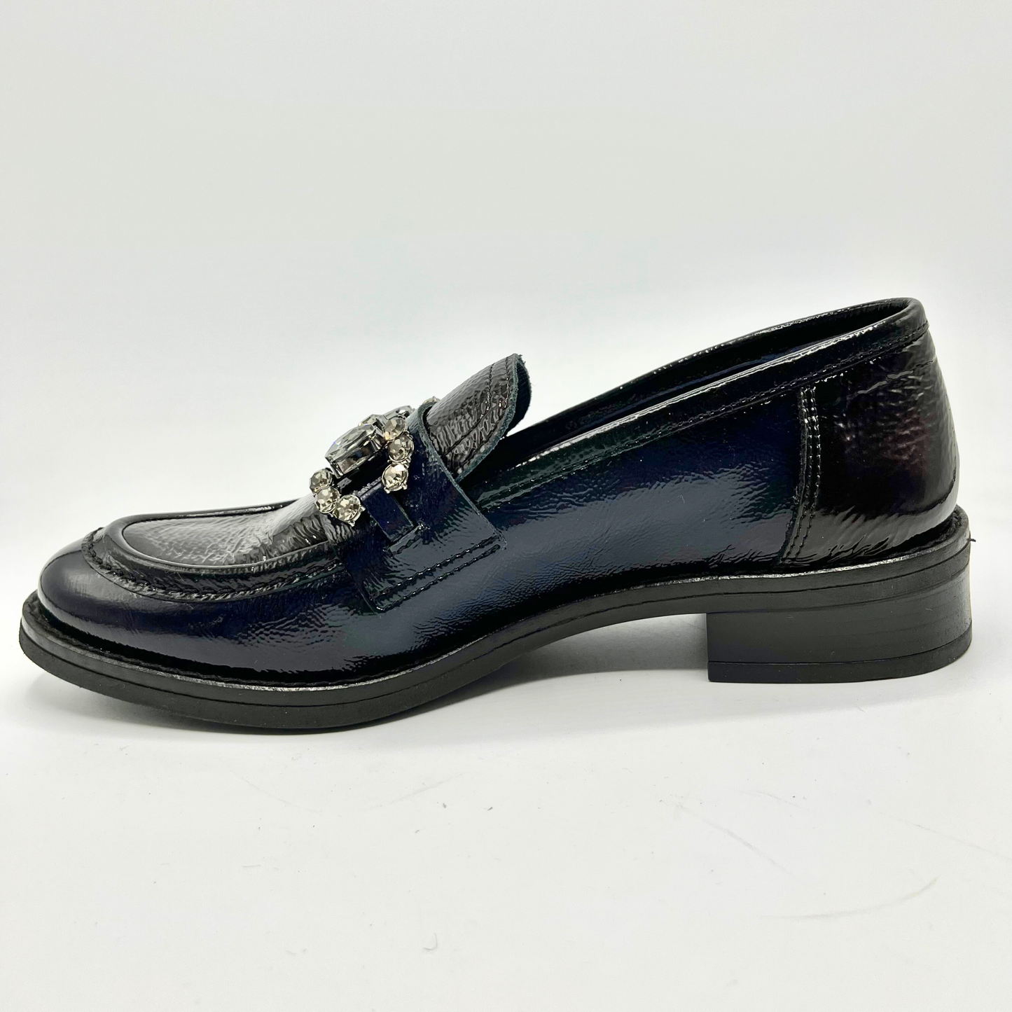 Navy patent leather loafer with decorative buckle on a white background