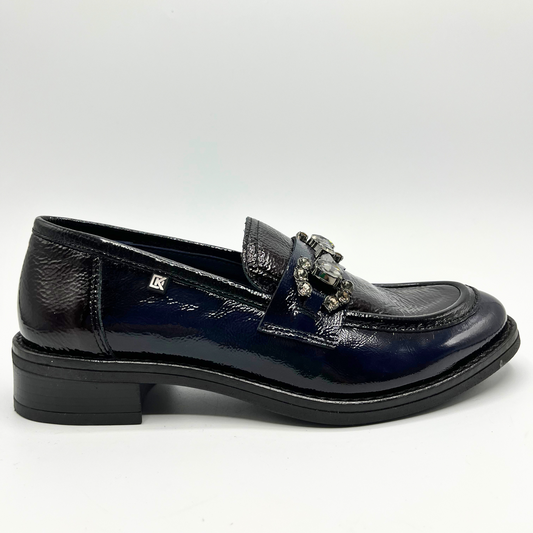 Navy patent leather loafer shoe on a light gray background