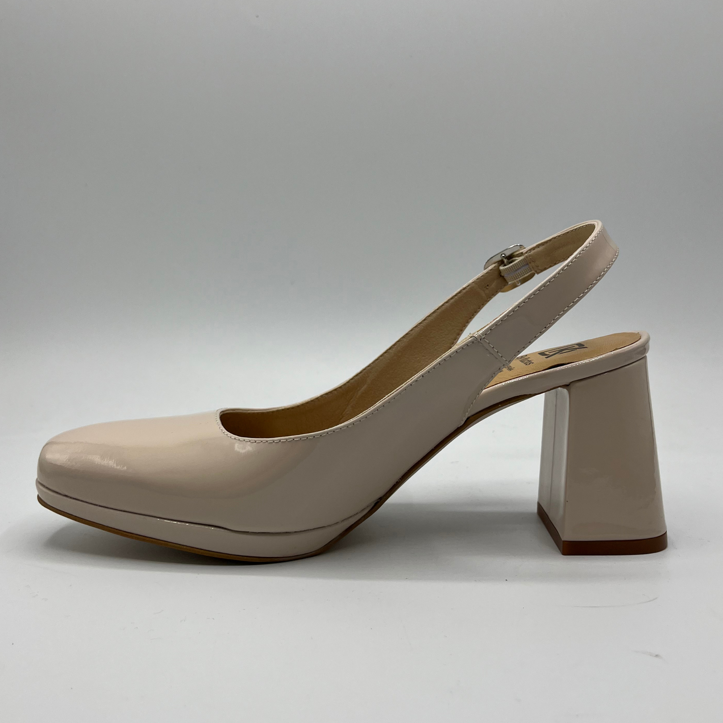 Left facing view of a nude patent leather high heeled shoe with an adjustable sling back strap and a leather insole.