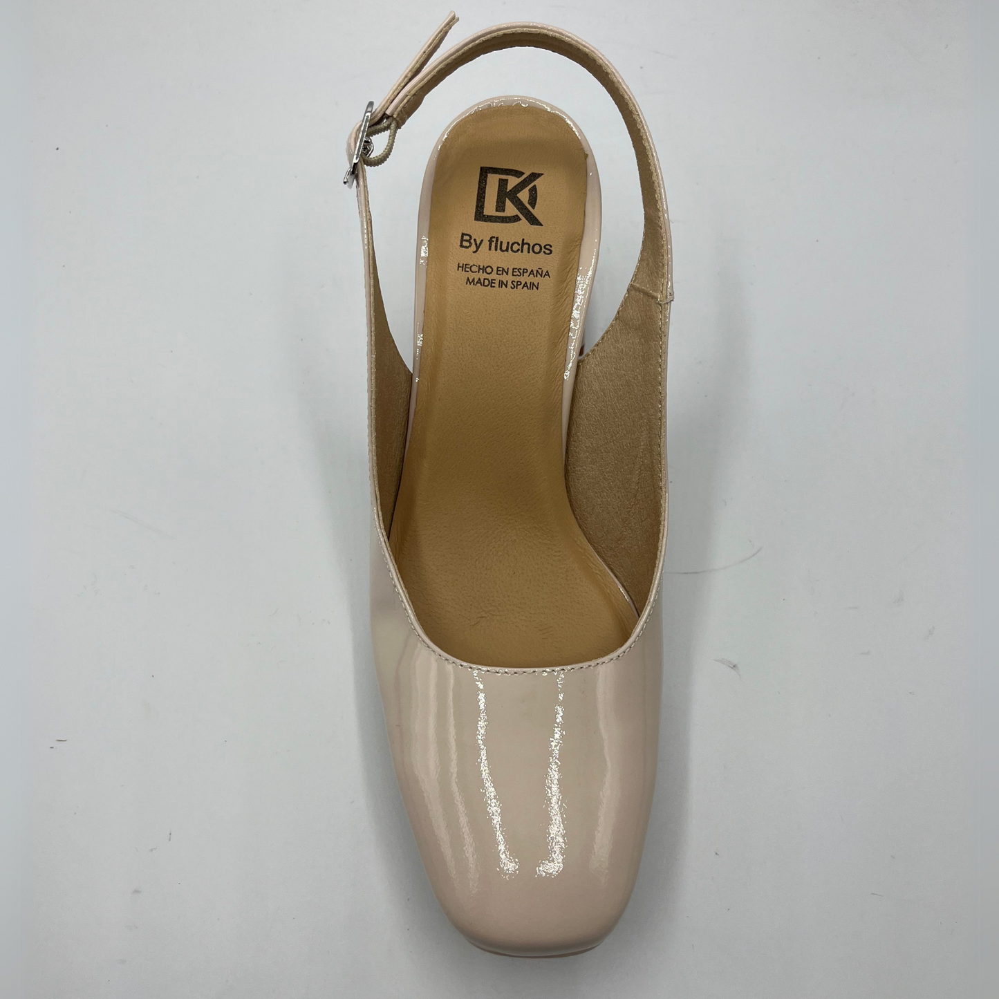 Top view of a nude patent leather high heeled shoe with an adjustable sling back strap and a leather insole.