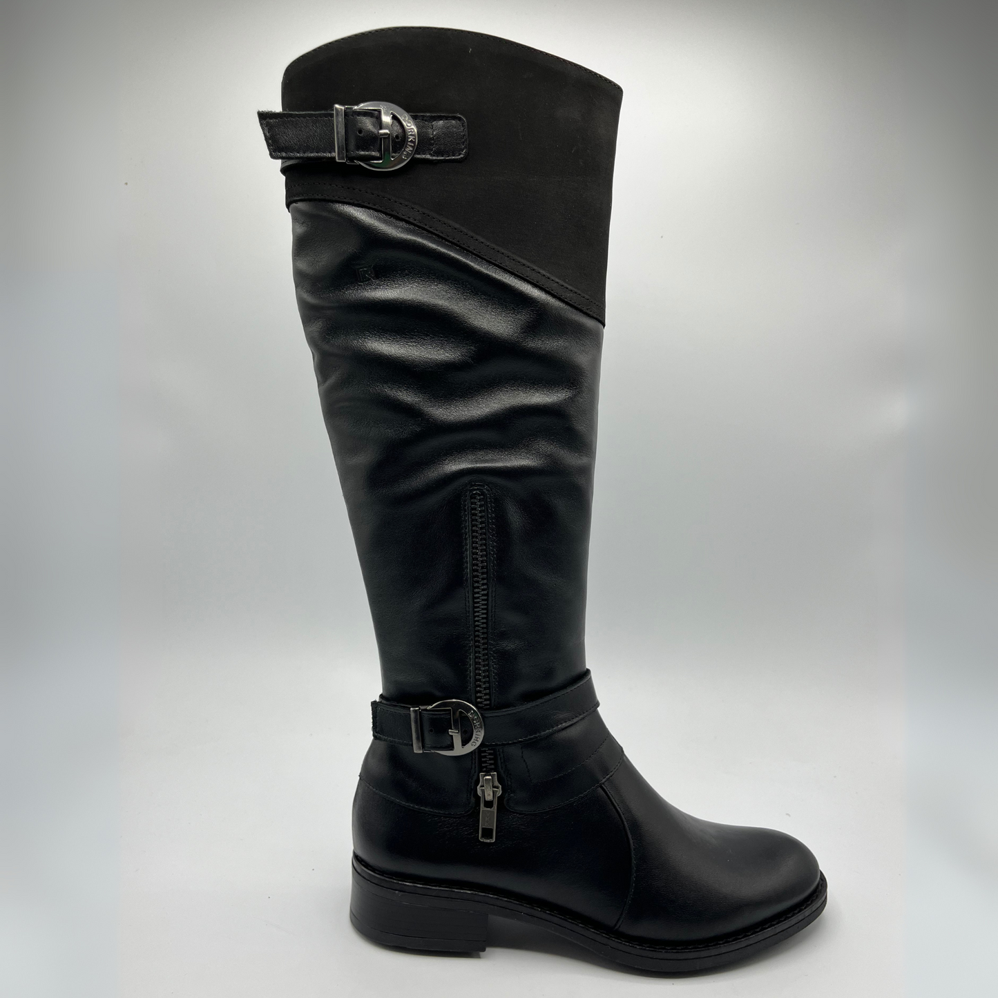 Black knee-high boot with silver buckles on a gray background