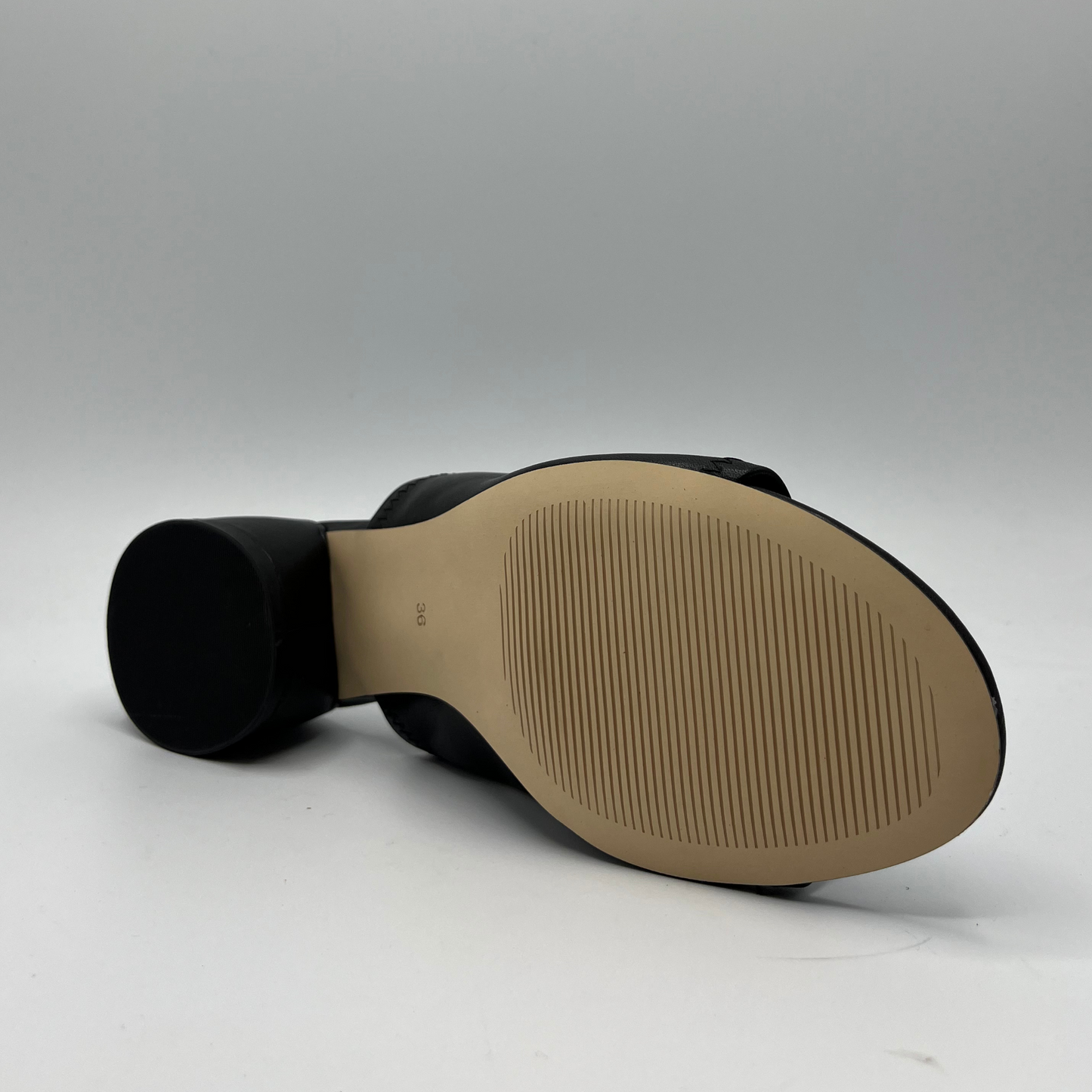 Bottom view of a black leather slip on sandal with a chunky rounded heel