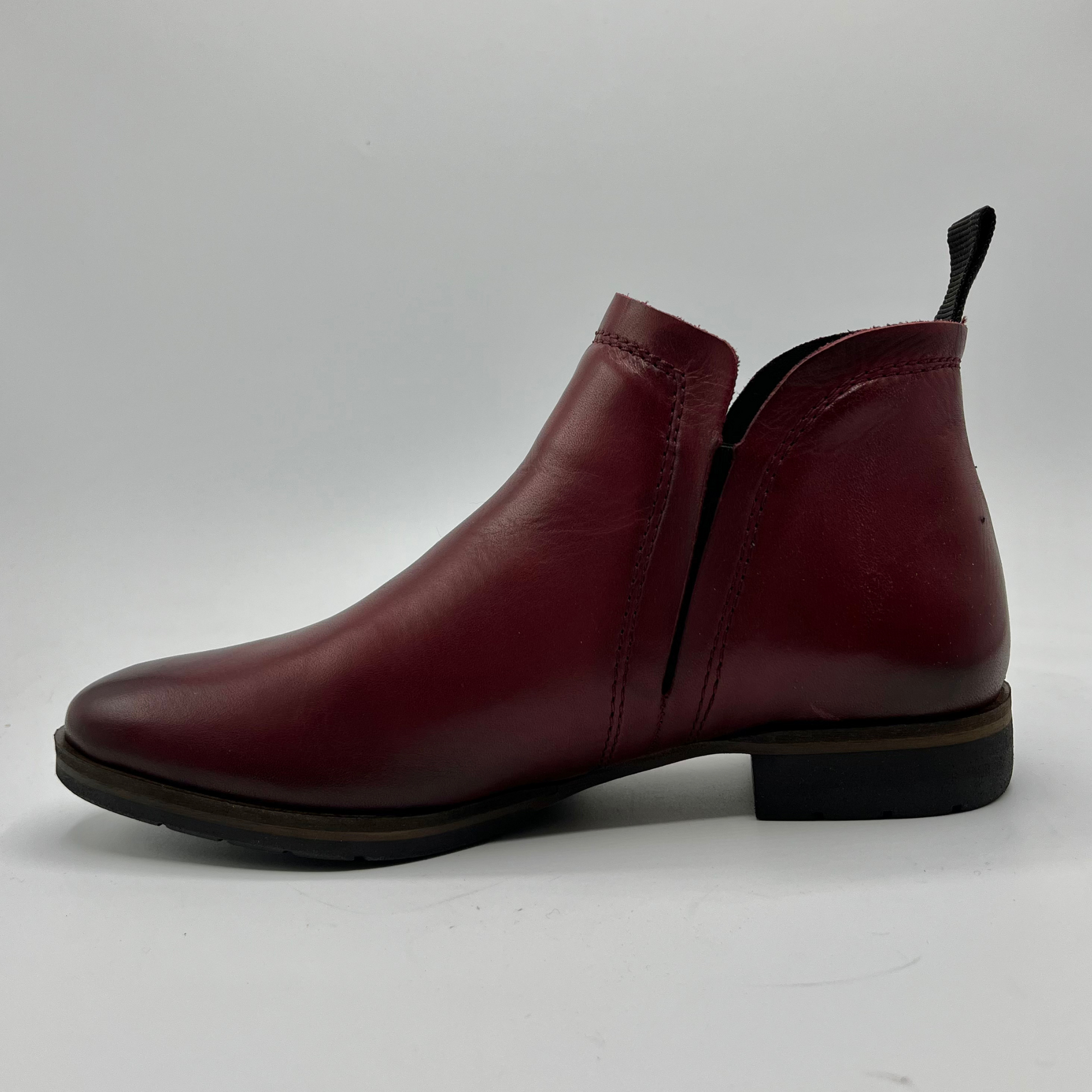 Single maroon leather boot on a white background