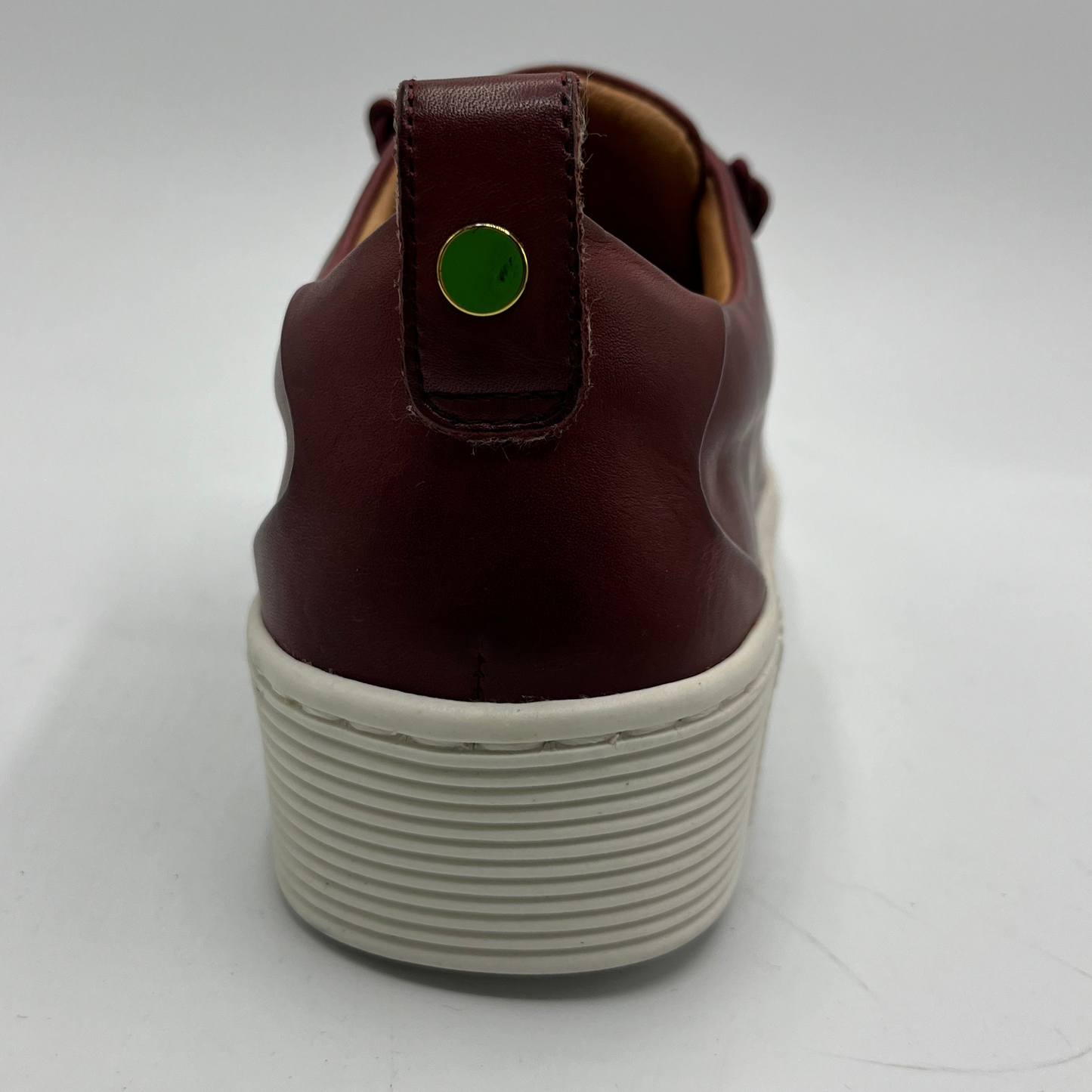 Brown sneaker with a green tag on a white background