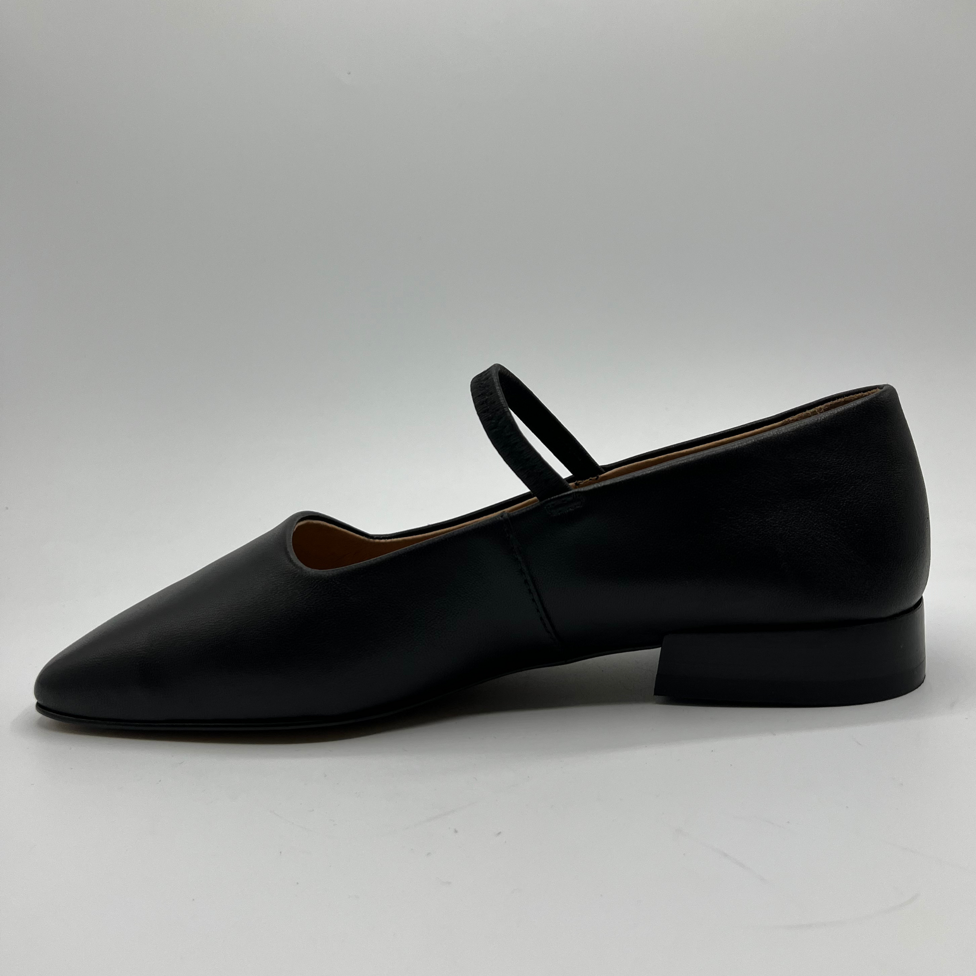 Black leather flat shoe on a light gray background