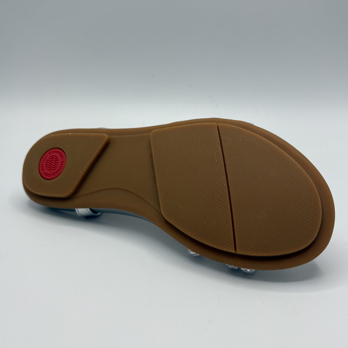 Brown sandal sole with a red label on a white background