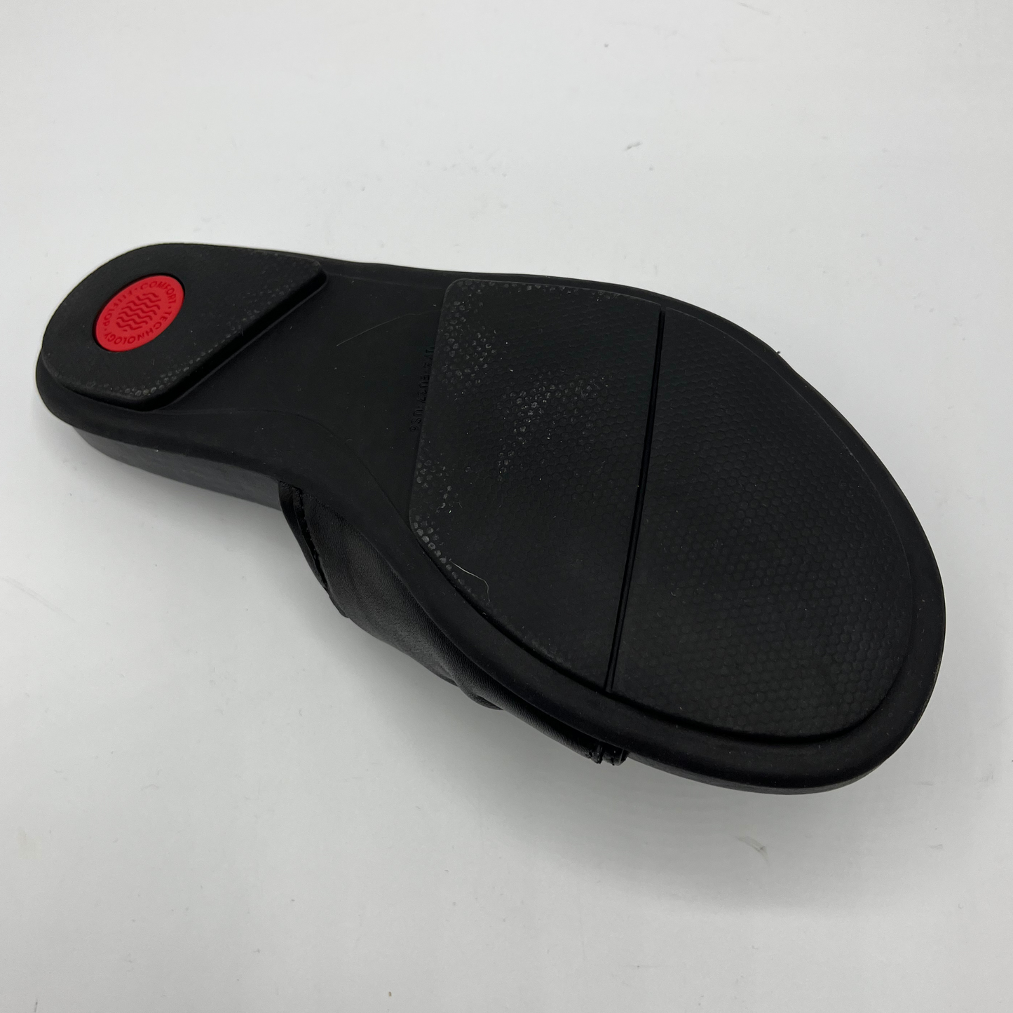 Bottom view of a black leather slip on sandal with a twisted accent on the upper. Contoured, cushioned footbed and rubber outsole.