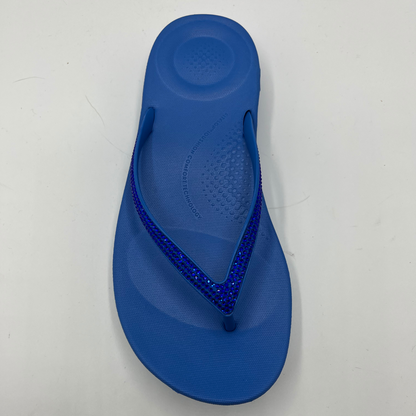 Top view of a cushioned blue slip flop sandal with a sparkly strap and cushioned footbed.