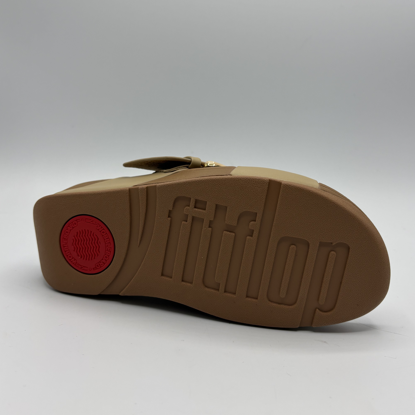 Brown sandal with 'fitflop' branding on a gray background