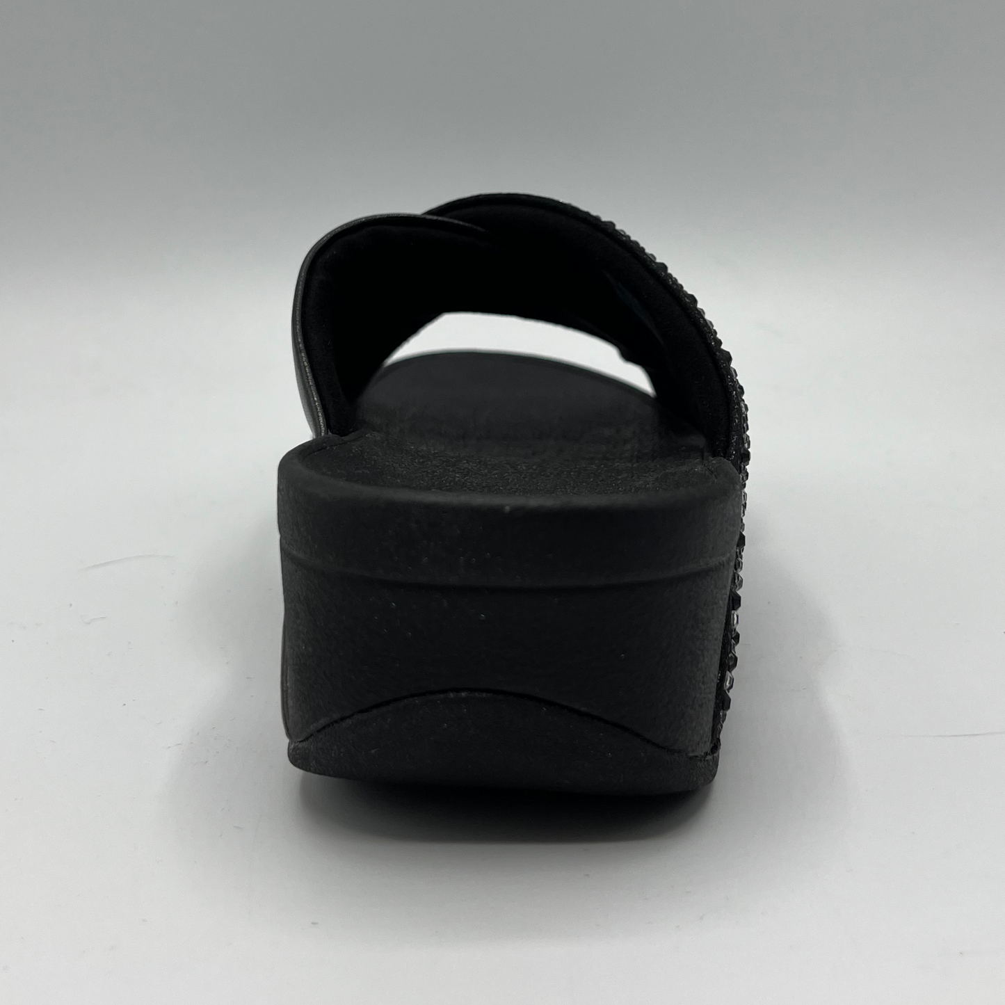 Back view of a black wedge sandal with two criss crossed straps, one is covered in small crystals.