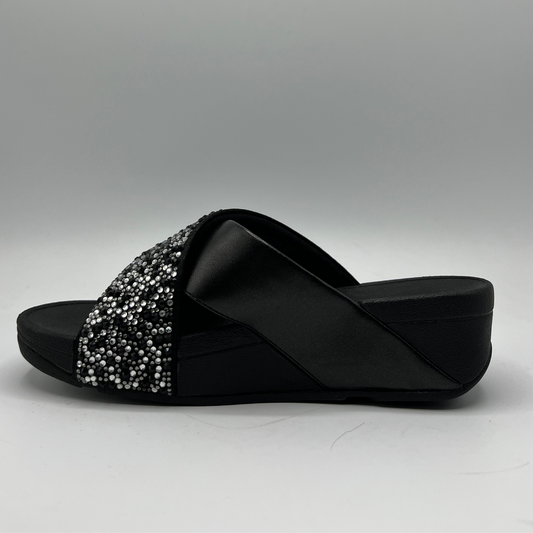 Left facing view of a black wedge sandal with two criss crossed straps, one is covered in small crystals.