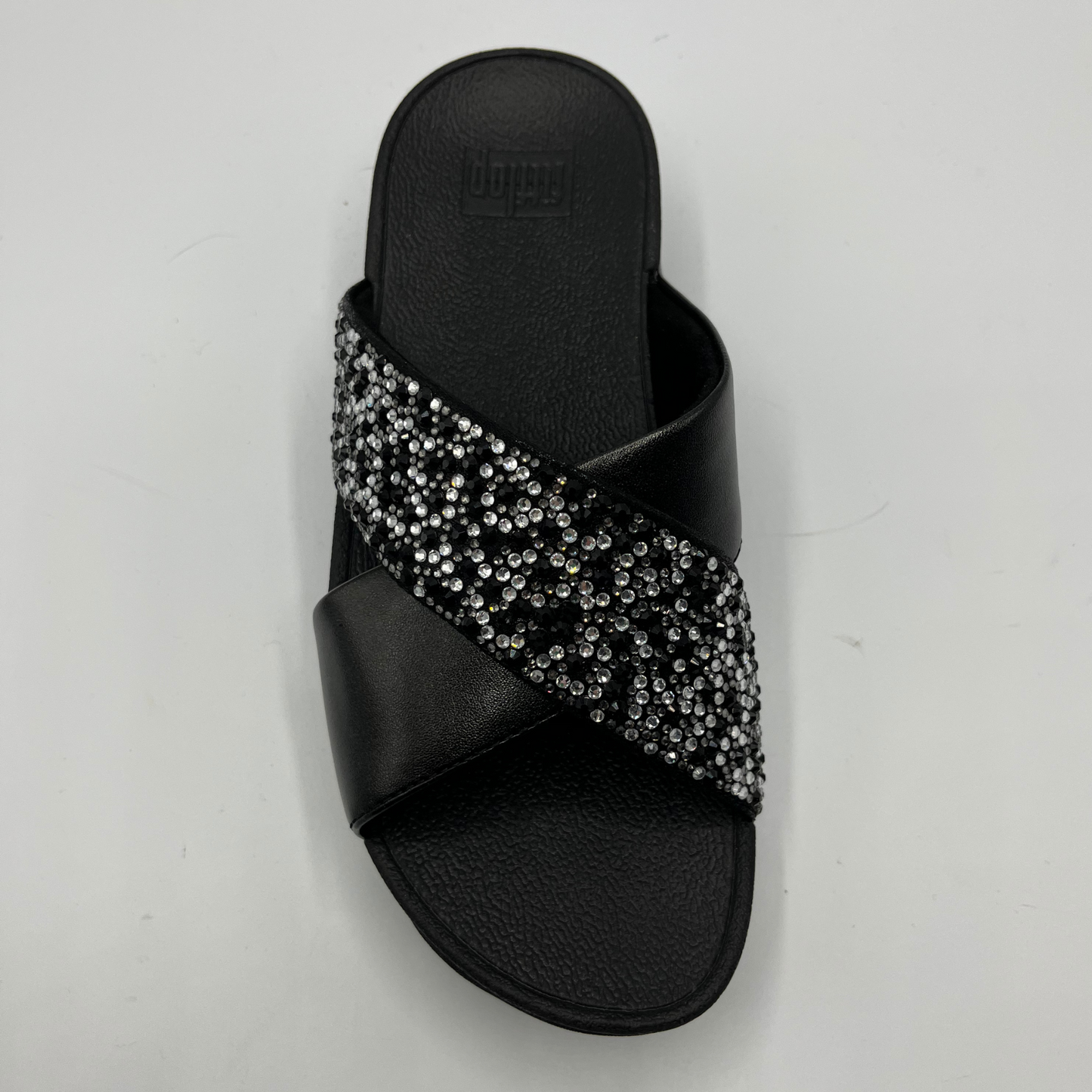 Top view of a black wedge sandal with two criss crossed straps, one is covered in small crystals.
