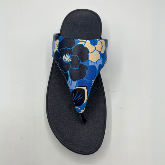 Top view of a slip on thong sandal with a blue floral strap and black wedge outsole.