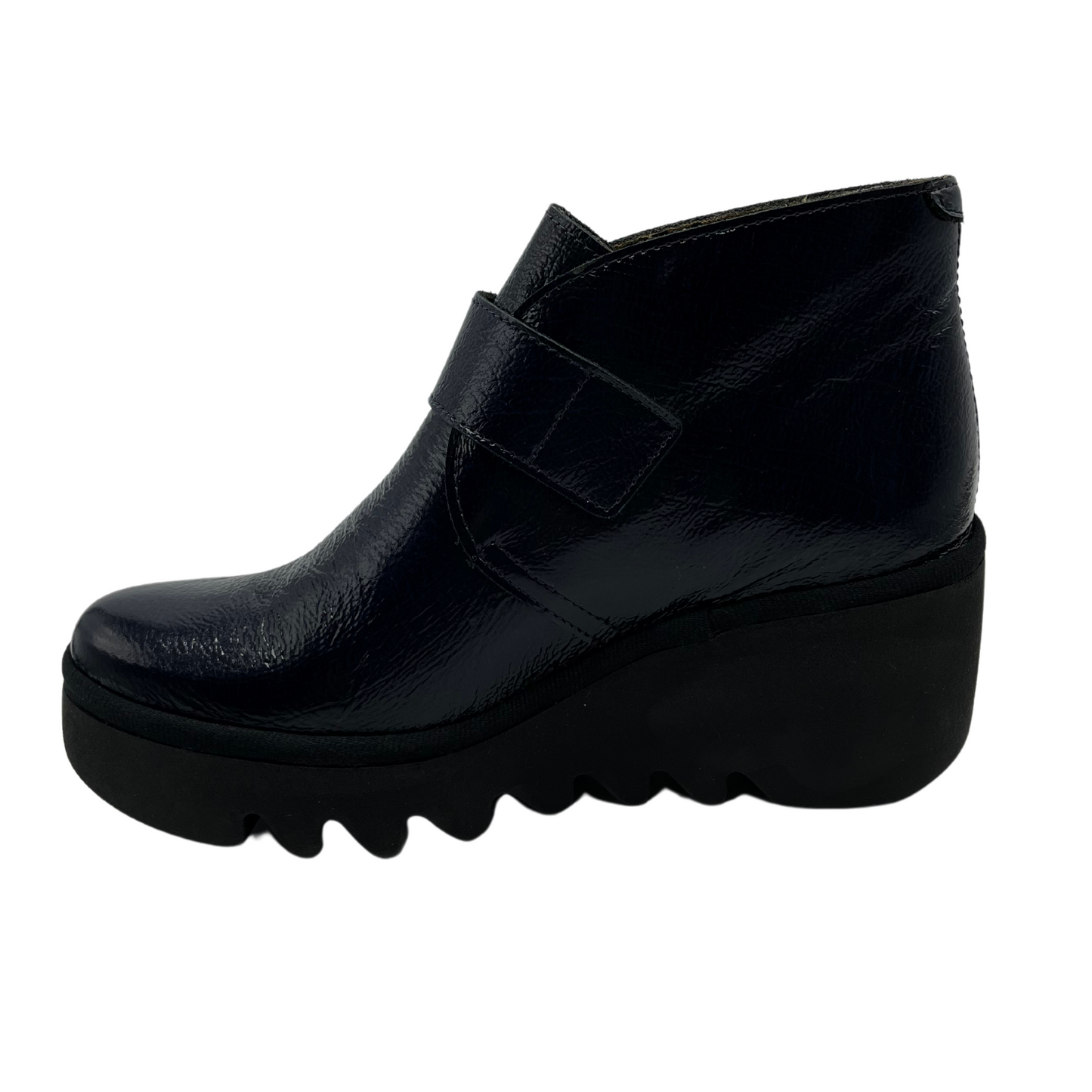 Left facing view navy patent leather wedge ankle boot with buckle strap and black outsole