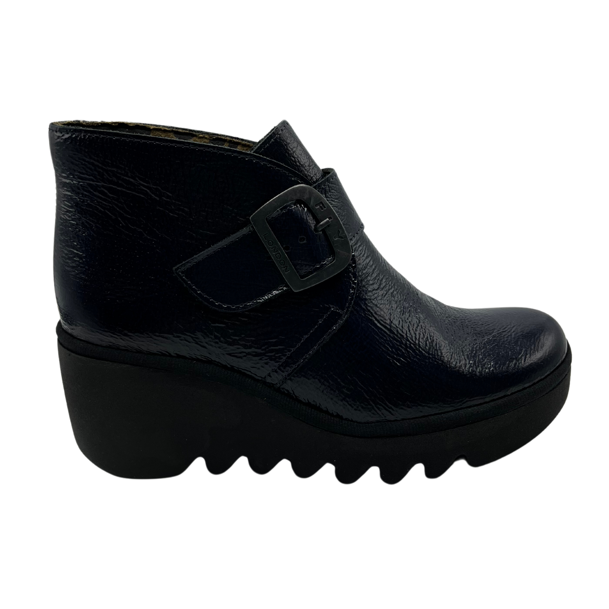 Right facing view navy patent leather wedge ankle boot with buckle strap and black outsole