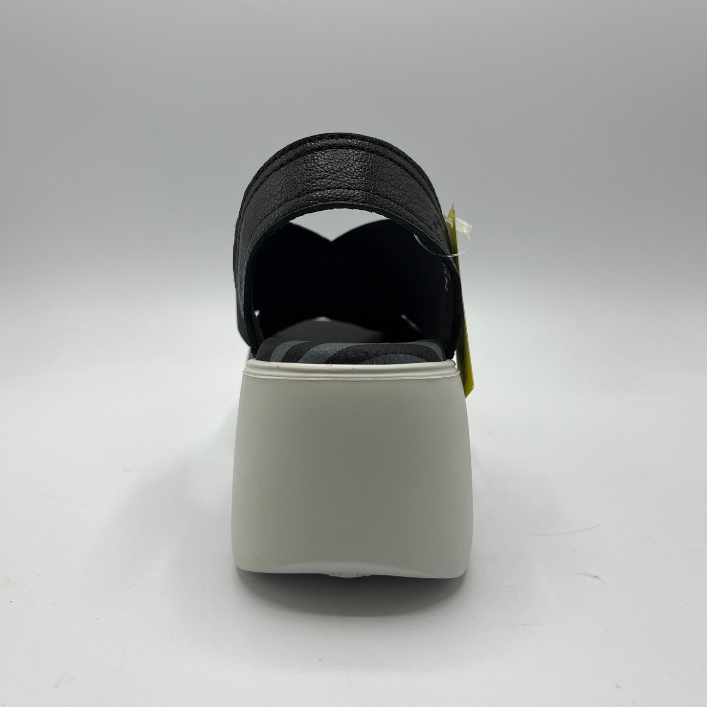 Back view of a black leather and elastic strapped sandal with white rubber wedge outsole