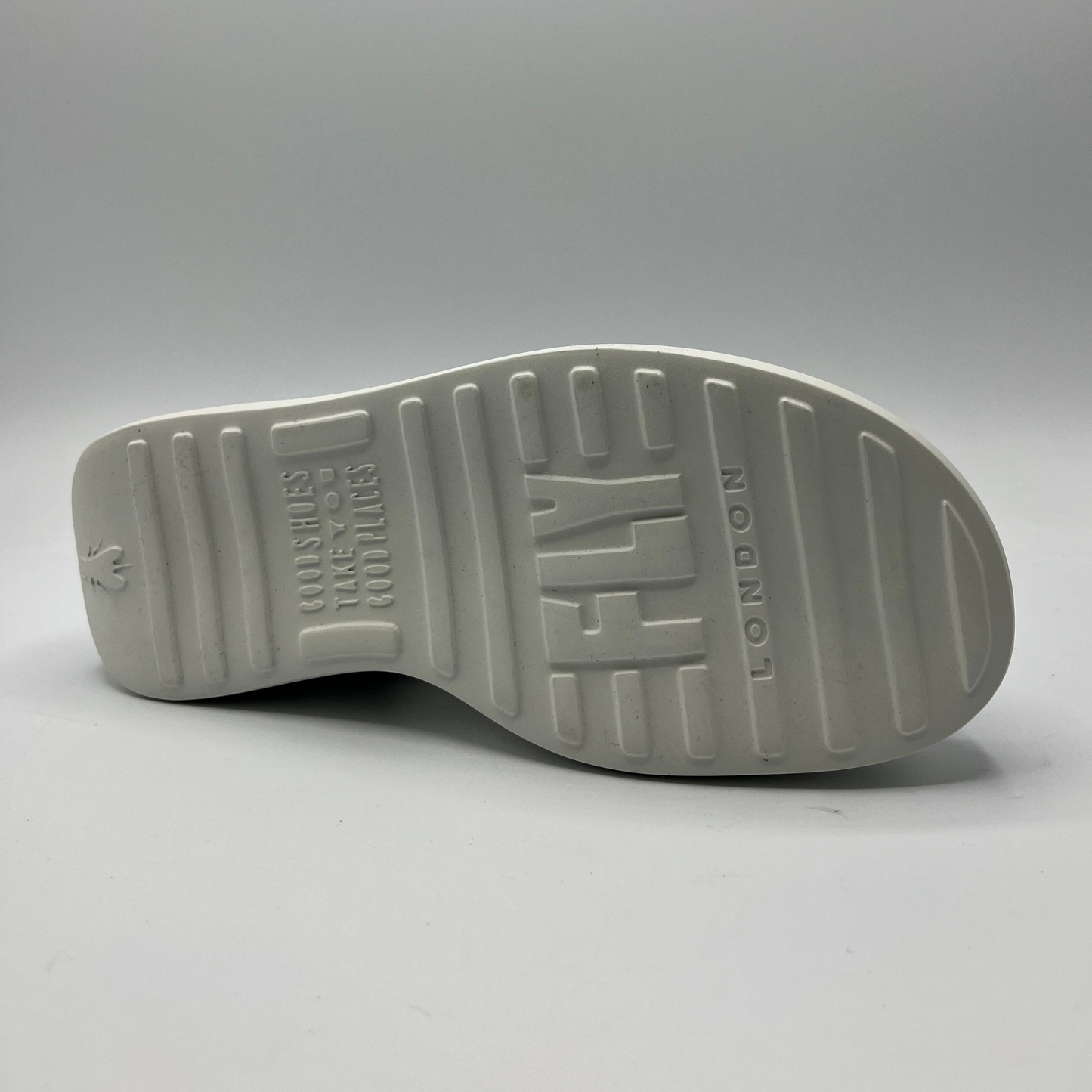 Bottom view of a black leather and elastic strapped sandal with white rubber wedge outsole