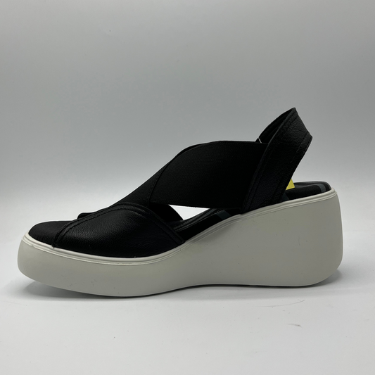 Left facing view of a black leather and elastic strapped sandal with white rubber wedge outsole