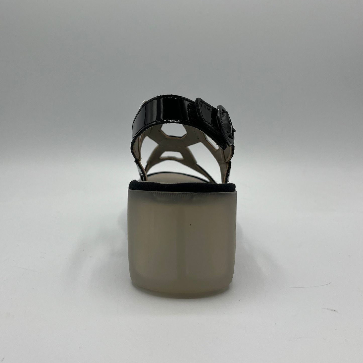 Back view of a black and white patent leather sandal with a lug platform sole and adjustable slingback strap.