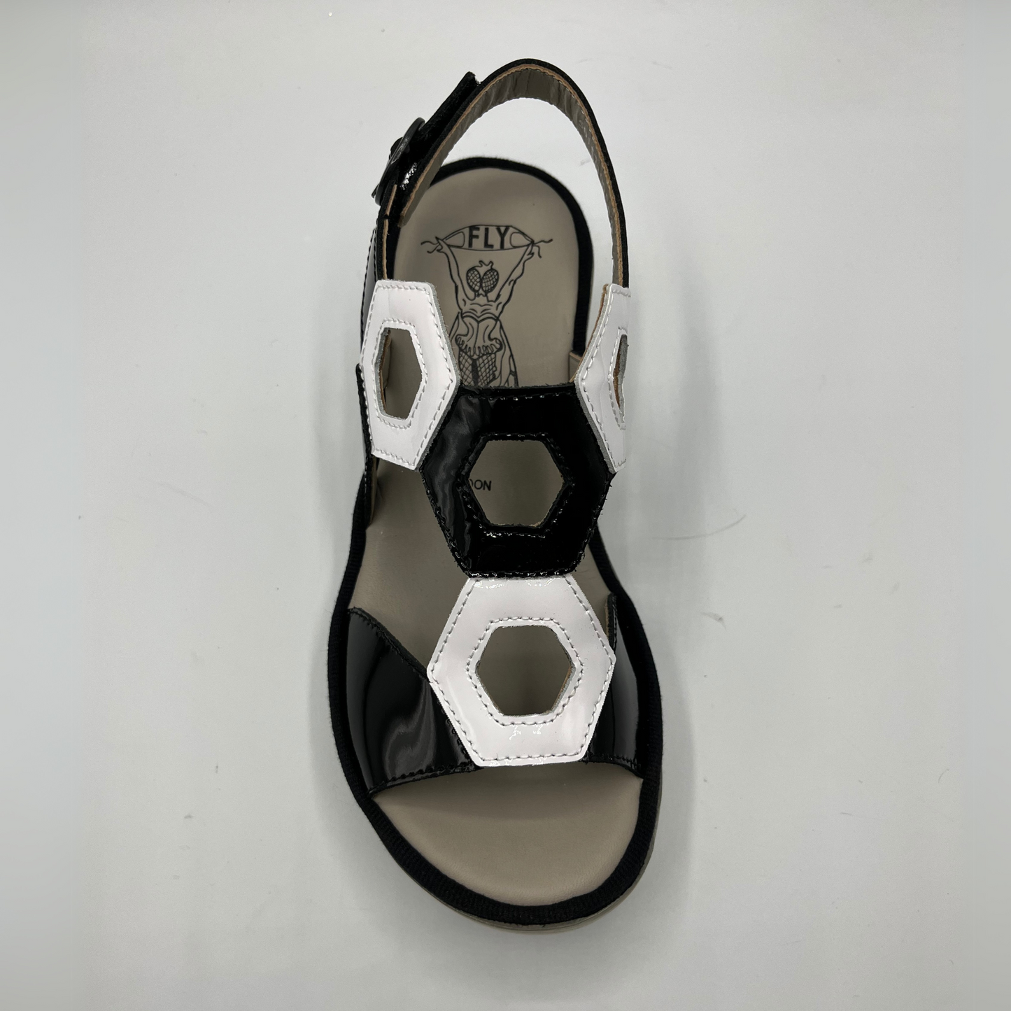 Top view of a black and white patent leather sandal with a lug platform sole and adjustable slingback strap.