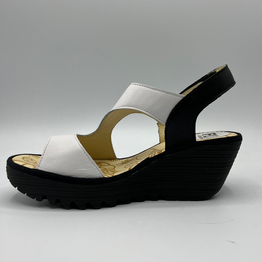 Left facing view of black and white leather strapped sandal with an adjustable velcro ankle strap and comfortable black wedge heel.