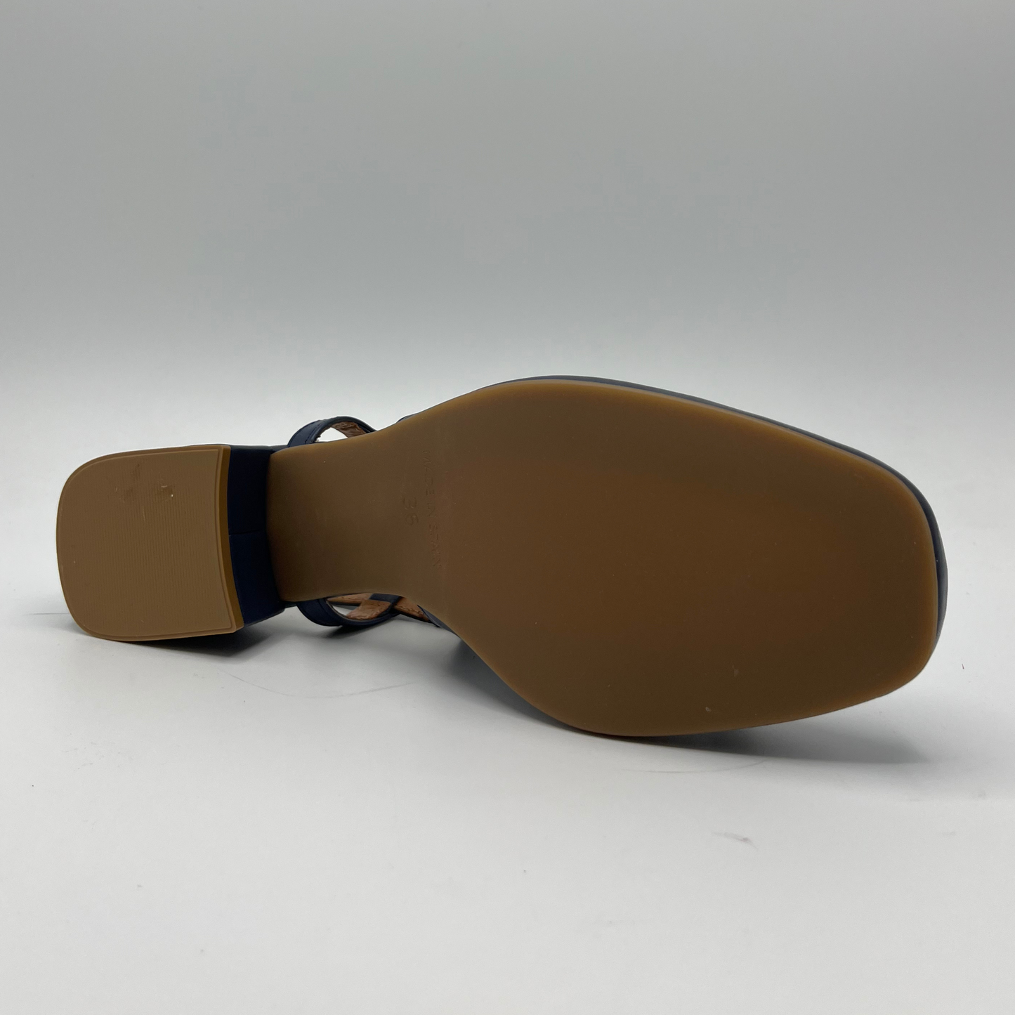 Bottom view of a navy leather slingback loafer with an adjustable buckle, wrapped heel and a squared toe.