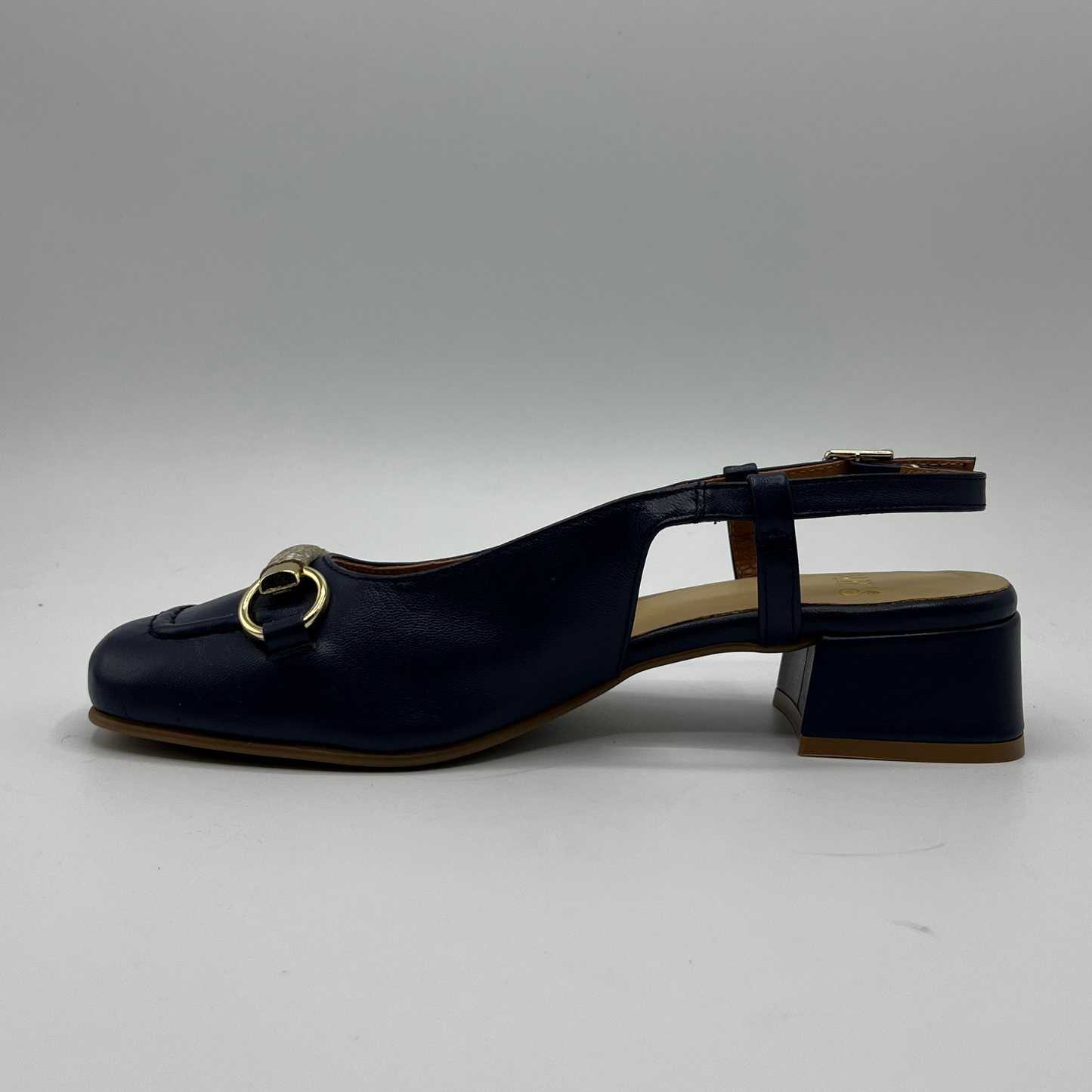 Left facing view of a navy leather slingback loafer with an adjustable buckle, wrapped heel and a squared toe.
