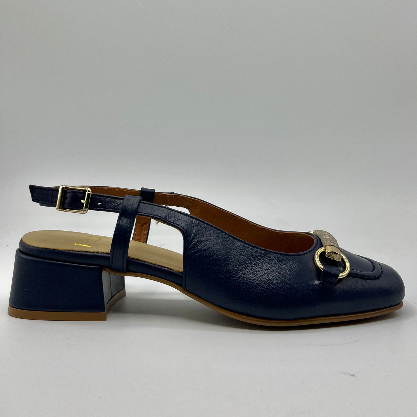 Right facing view of a navy leather slingback loafer with an adjustable buckle, wrapped heel and a squared toe.