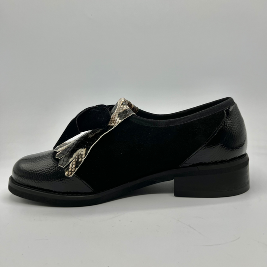 Black shoe with a metallic strap on a gray background