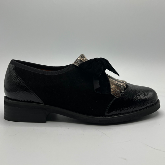 Black leather shoe with decorative bow on a white background