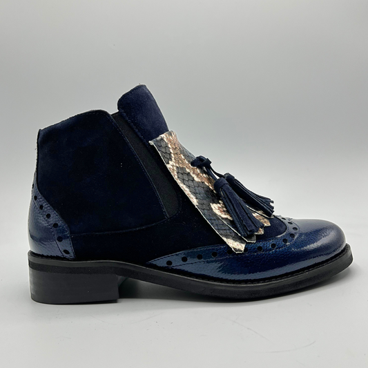 Navy blue shoe with tassel detail on a gray background