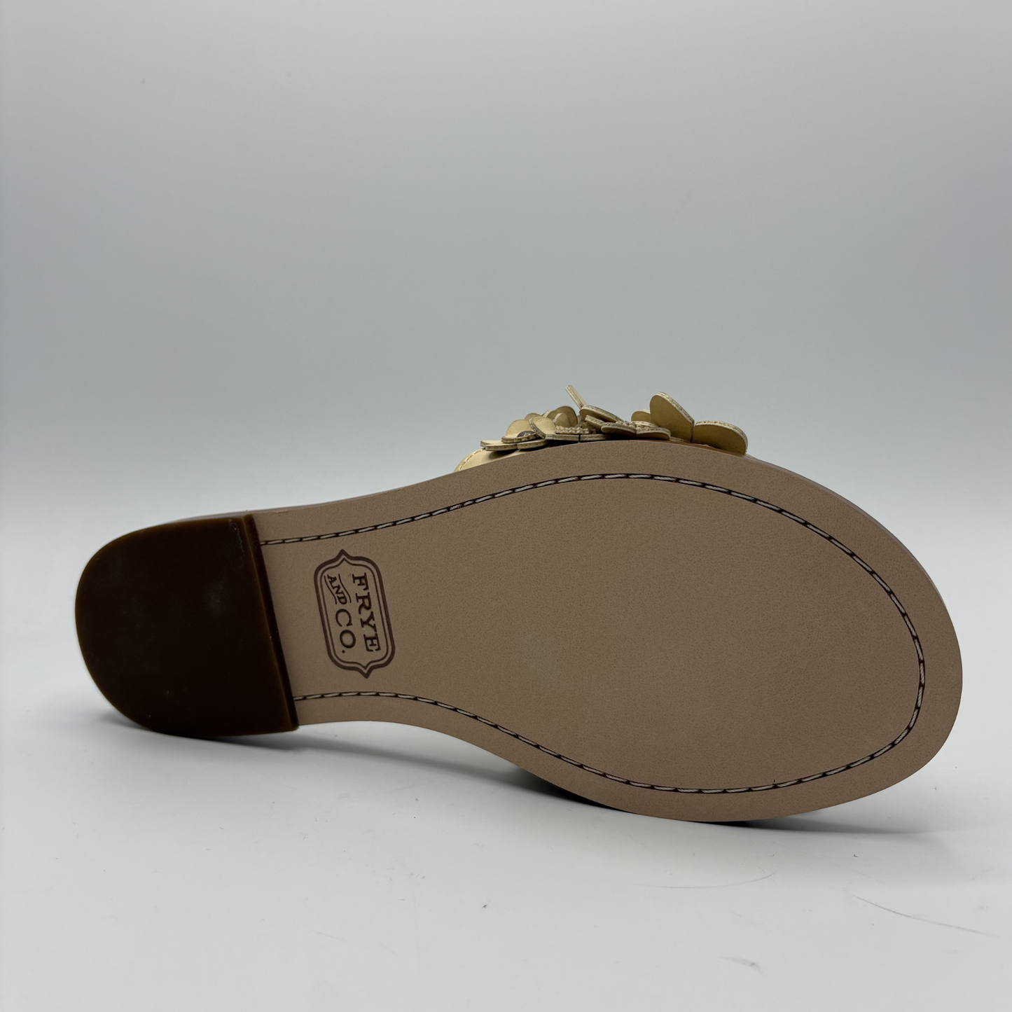 Brown sandal sole with gold chain detail on a white background