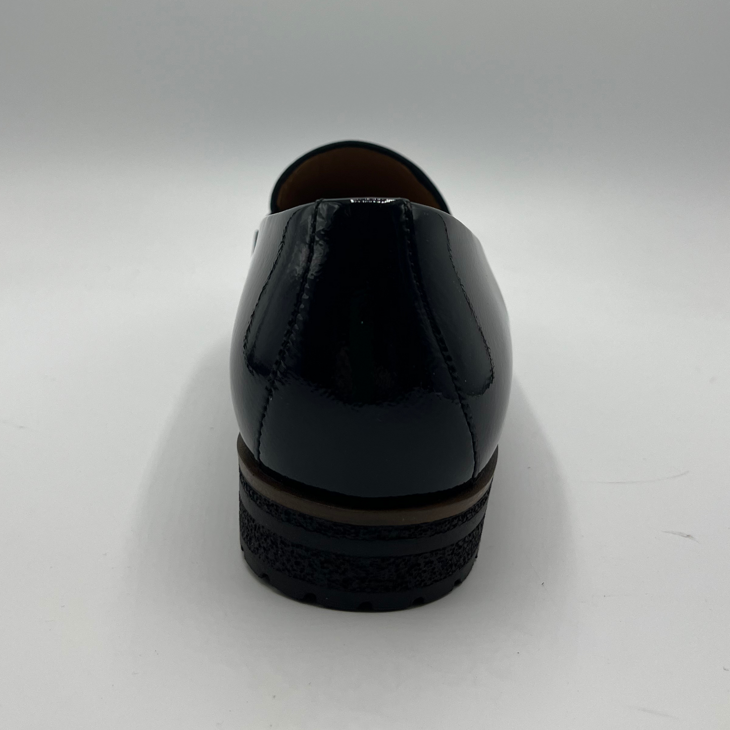 Back view of a black leather loafer with a tan lining