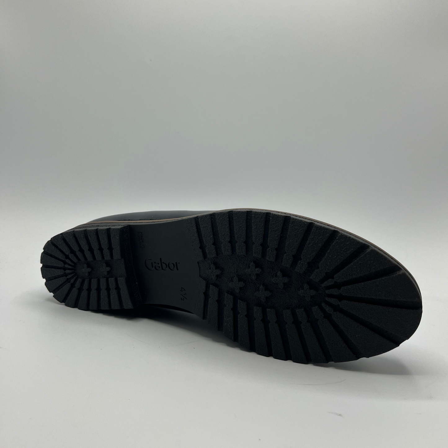 Bottom view of a black leather loafer with a tan lining