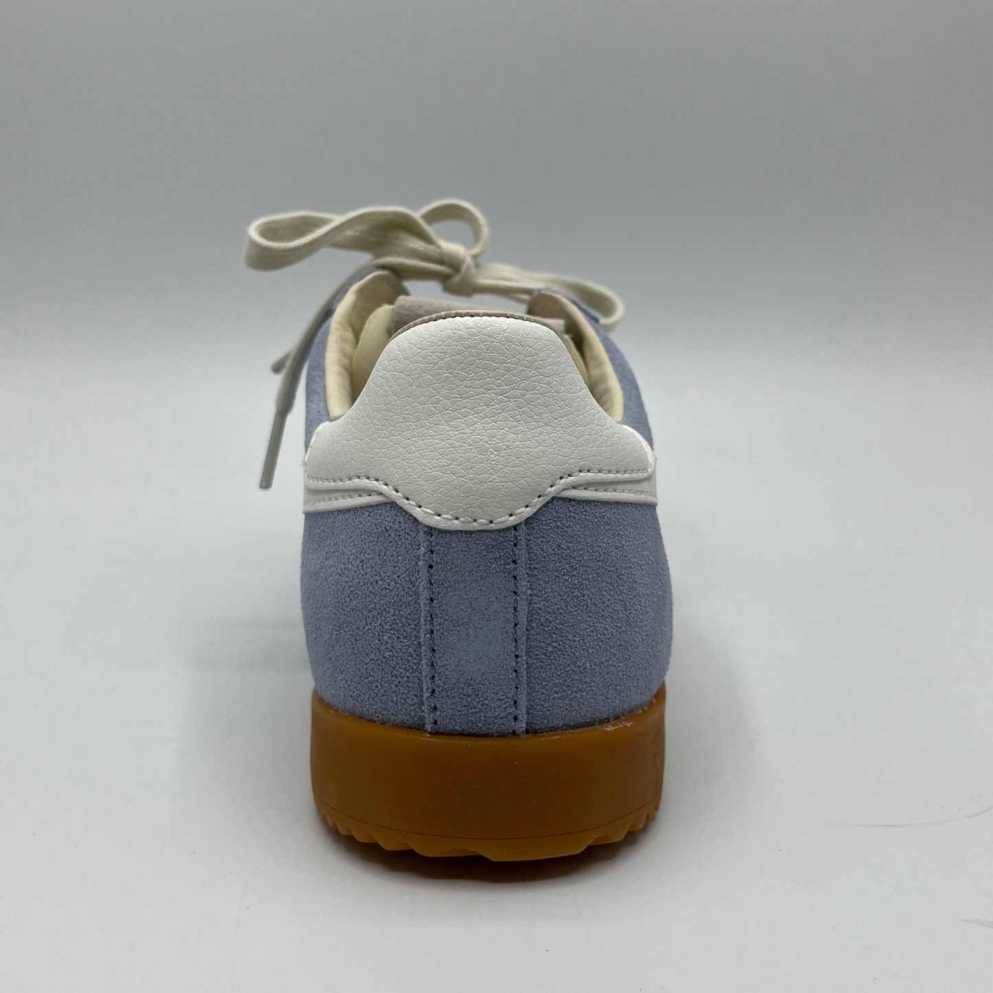 Back view of a blue suede sneaker with white accents, a gum outsole and a lace up design.