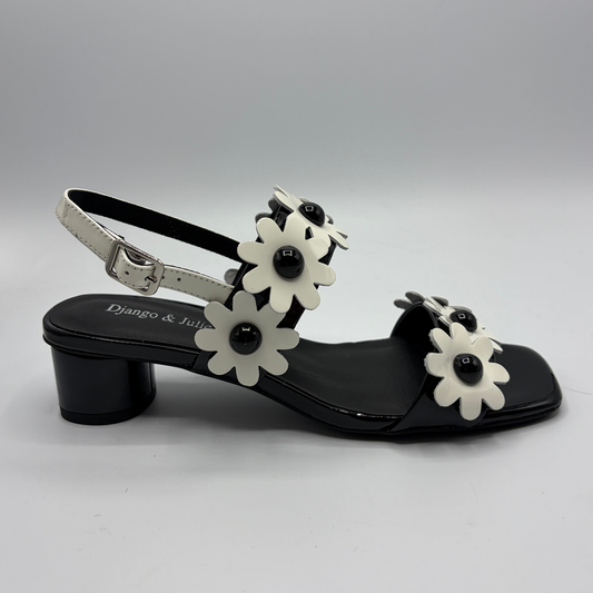 Black sandal with white floral decorations on a gray background