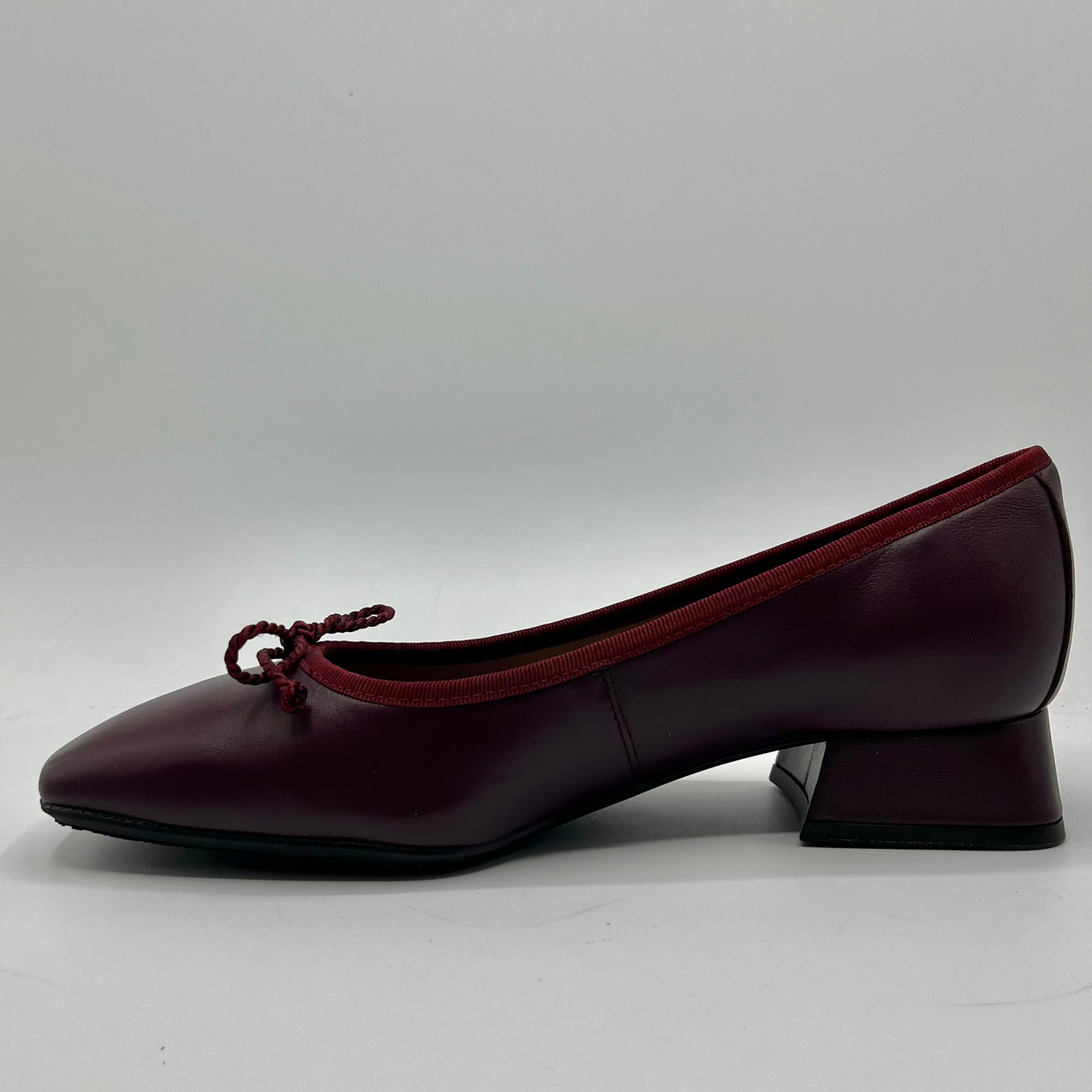 Burgundy shoe with a red bow on a white background