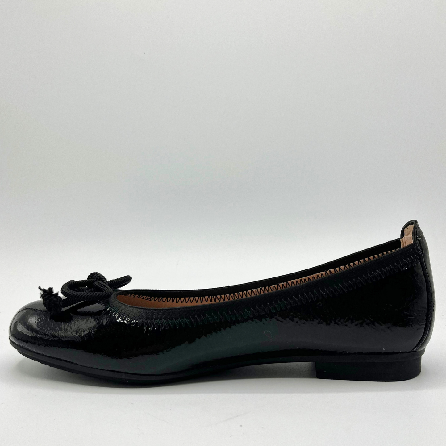Black patent leather flat shoe on a white background