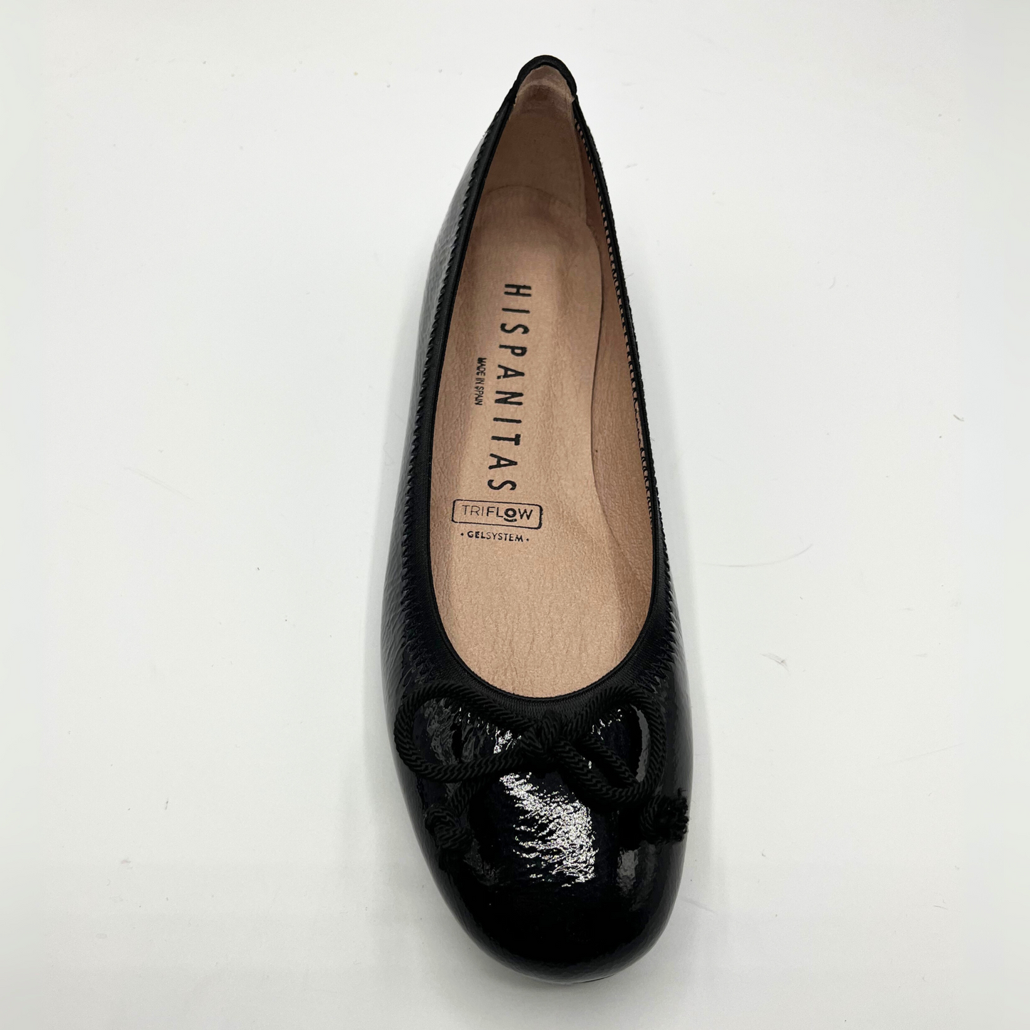 Black patent leather flat shoe on a white background