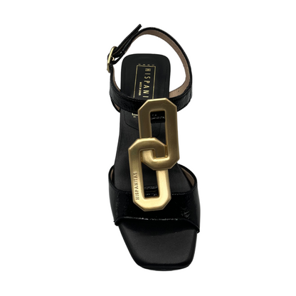 Top view of black patent leather sandals with square toe and gold brooch detail on upper