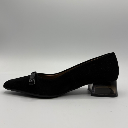 A single black pointed-toe pump shoe with a small bow detail on the strap, set against a neutral gray studio background.