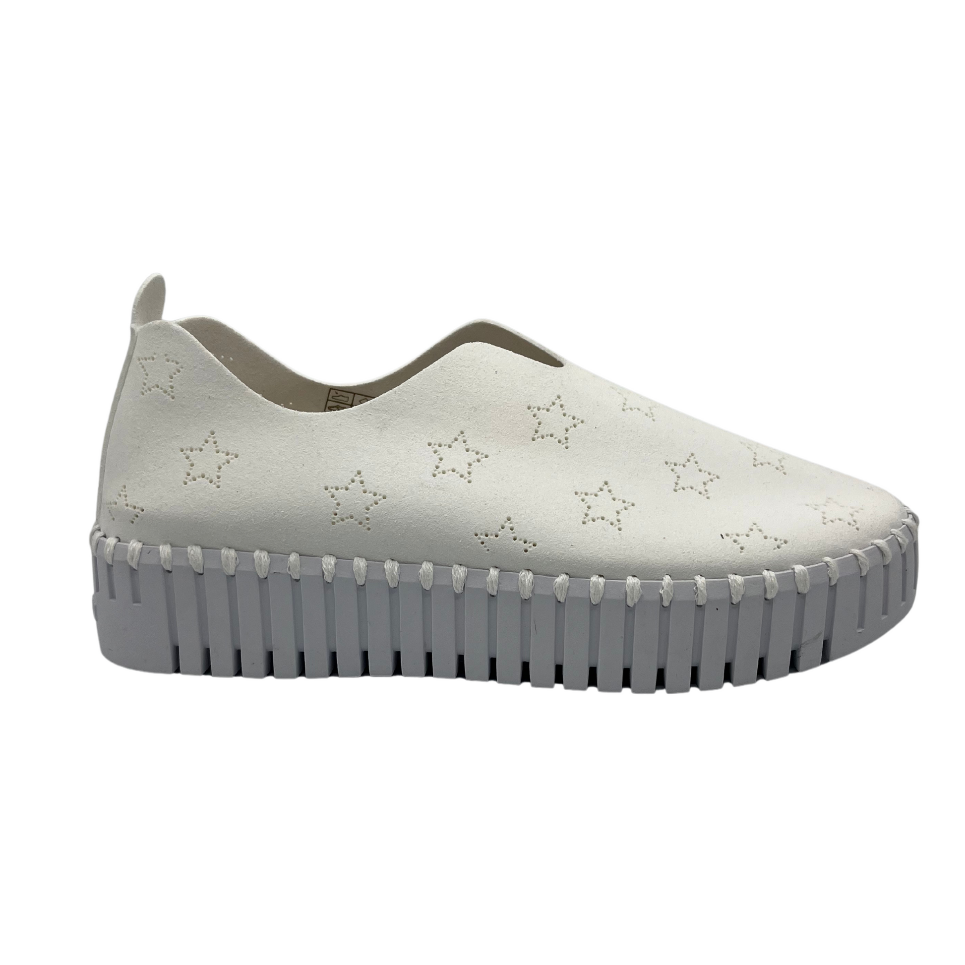 Right facing view of white slip on sneakers with small star cutouts on upper. White rubber platform sole.