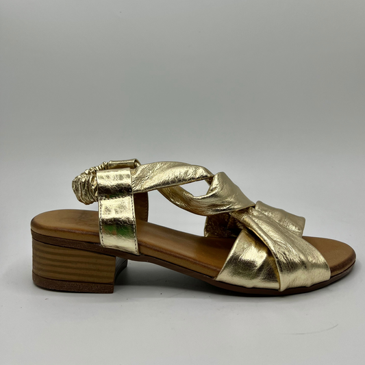 Right facing view of a gold leather sandal with a tan leather wrapped footbed and a short stacked heel.