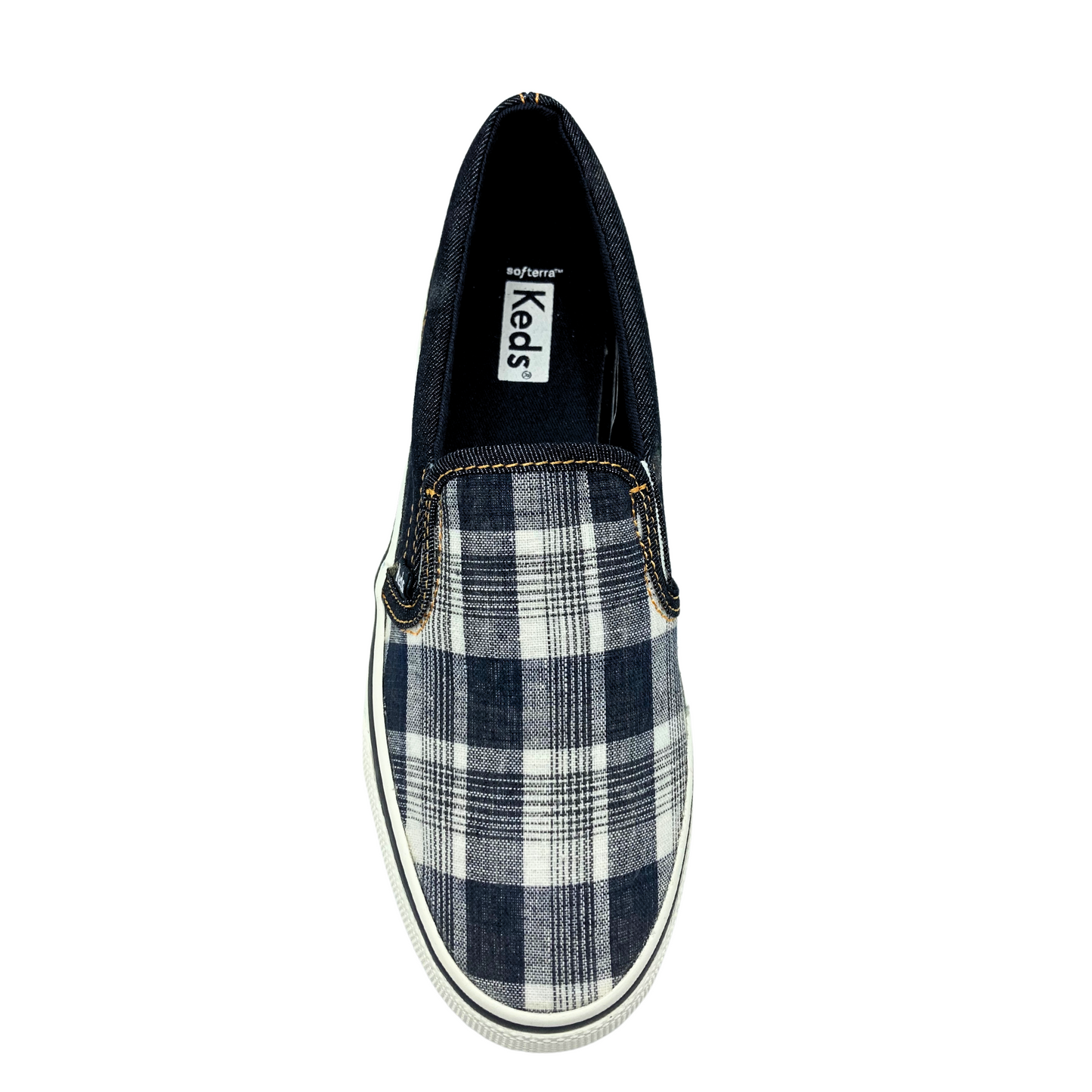 Top down view of a canvas slip on sneaker by Keds. Black plaid on the top and denim around the heel