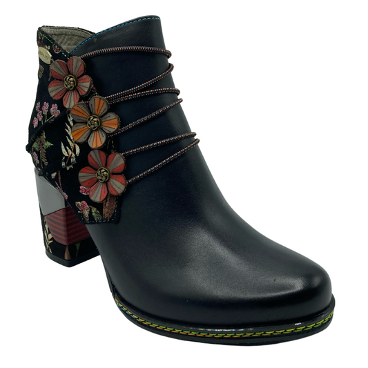 45 degree angled view of black leather ankle boot with floral details surrounding the block heel and back of upper 