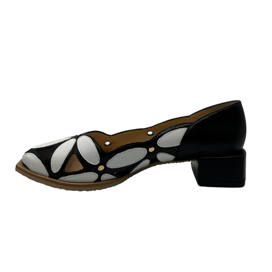 Left facing view of black and white leather shoe with a black short block heel and floral style appliques on upper.