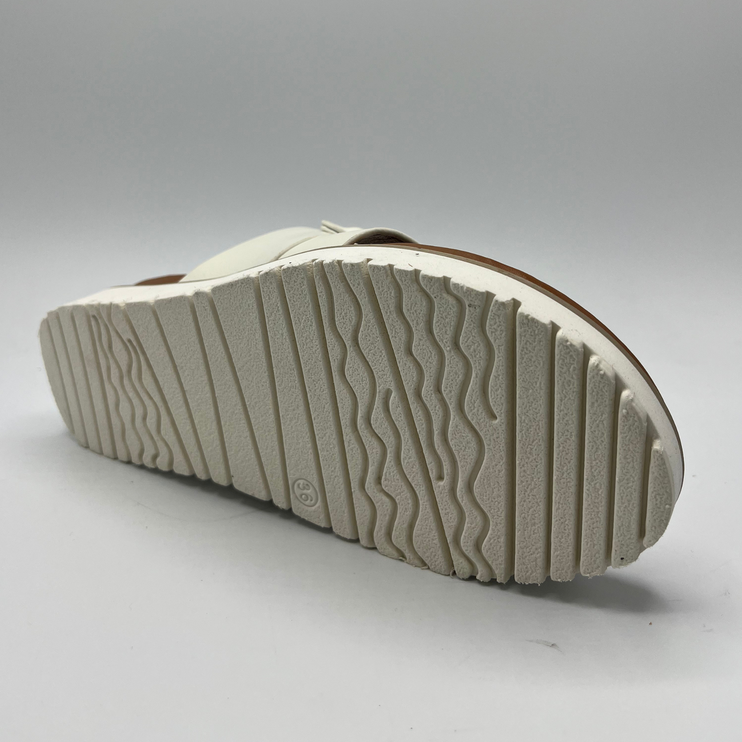 Bottom view of a white slip on sandal with a toe strap and chunky platform outsole.