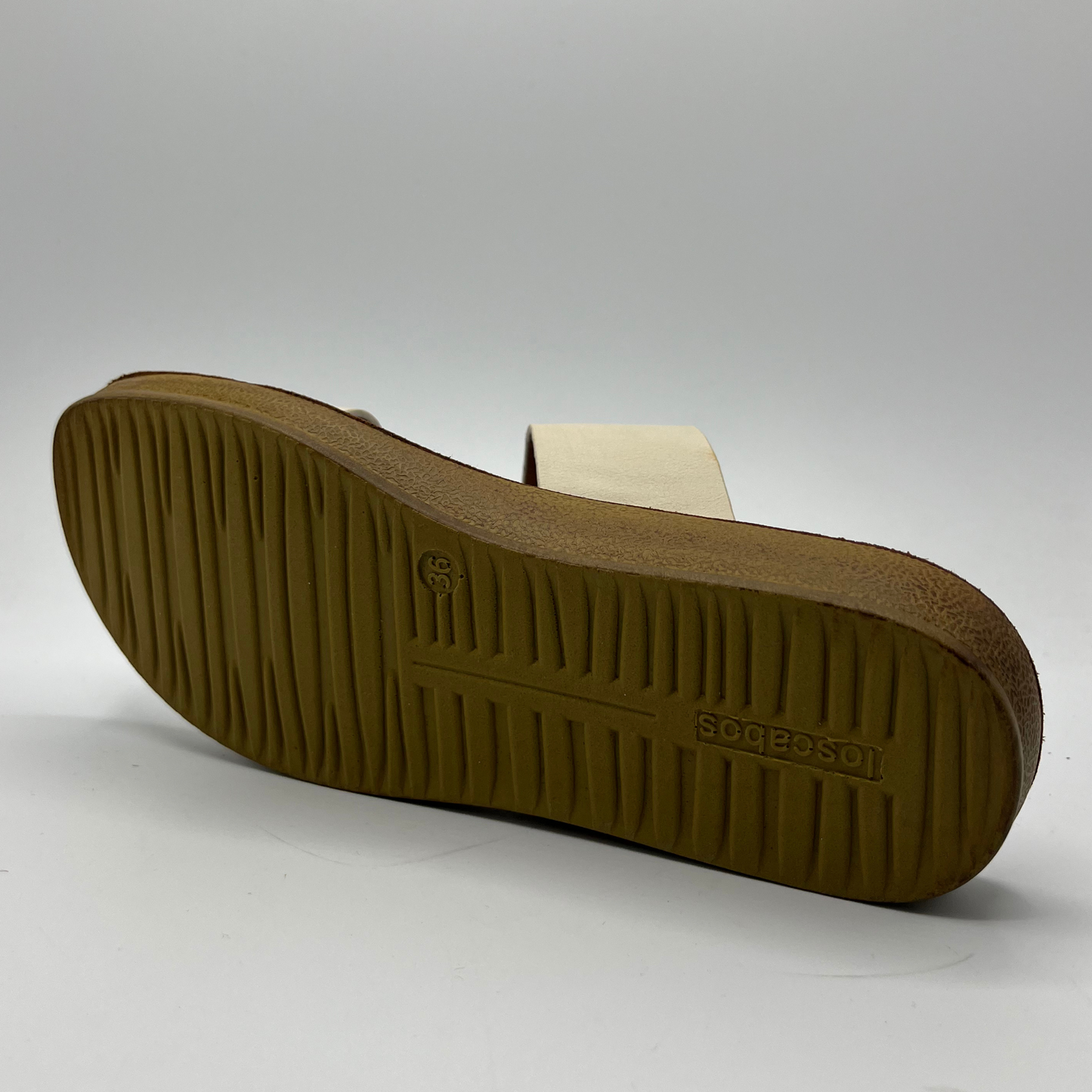 Bottom view of a bone white strapped sandal with a brown footbed